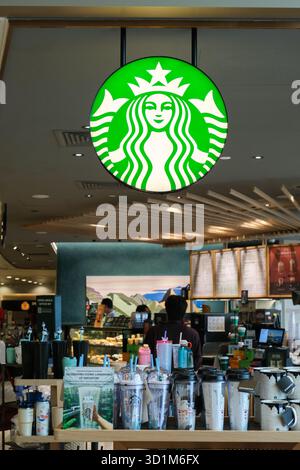 Das Starbucks-Geschäft am Flughafen Changi verfügt über ein grünes Logo, Holzakzente und zwanglose Sitzgelegenheiten. Die Menschen genießen Drinks in einer modernen Umgebung. Stockfoto