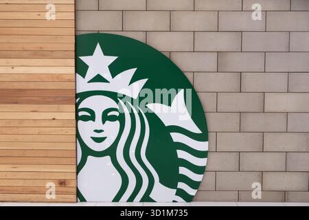 Penang, Malaysia – 16. Oktober 2025: Ein großes grünes Starbucks-Logo ist an einer Holzwand sichtbar, mit glattem Finish und weißem Detailin Stockfoto