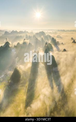 Die majestätischen Gipfel aus der Luft durchdringen ein Meer aus ätherischem Nebel, Sonnenlicht wirft lange Schatten über die Landschaft, Cao Bang, Vietnam. Stockfoto