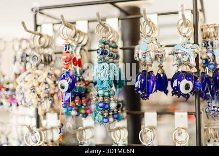 Eine lebendige Kollektion von handgefertigtem Schmuck hängt auf einem Ausstellungsregal. Die farbenfrohen Stücke sind mit Glasperlen und einzigartigen Designs versehen und faszinieren Käufer Stockfoto