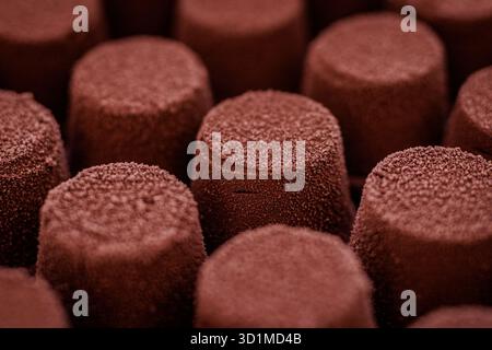 Nahaufnahme kleiner Schokoladenmousse-Desserts mit weicher Samtstruktur in Reihen. Stockfoto