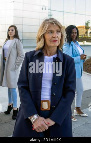 Drei Frauen mit unterschiedlichen Stilen posieren selbstbewusst außerhalb eines eleganten Büroaufbaus. Die Sonne scheint hell, wenn sie Kraft und Kameradschaft in Th zeigen Stockfoto