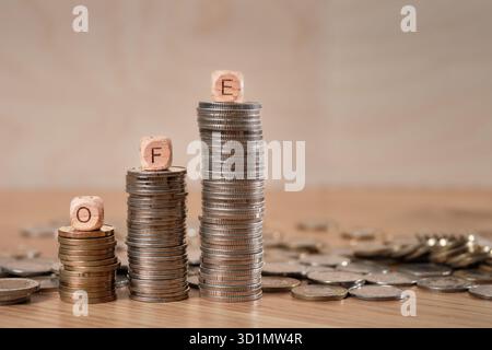 Holzwürfel mit den Buchstaben OFE (Open Pension Fund â€“ Otwarty Fundusz Emerytalny), angeordnet auf Stapeln polnischer Münzen, die das Rentenersparnis und das Kapitalwachstum darstellen. Stockfoto