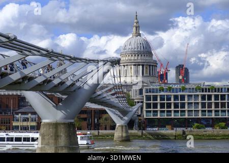 St Paul's Cathedral und Millennium Footbridge über die Themse, während ein Boot die Brücke in London überquert Stockfoto