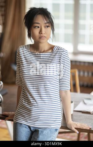 Zu Hause. Junge asiatische Frau in gestreiftem Hemd zu Hause Stockfoto