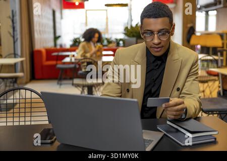 Arbeiten. Junger Geschäftsmann, der an einem Laptop arbeitet und sich beteiligt sieht Stockfoto