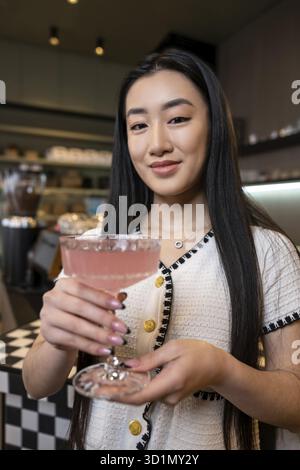 Porträt einer süßen jungen Frau, die mit einem Glas Cocktail vor der Kamera posiert Stockfoto