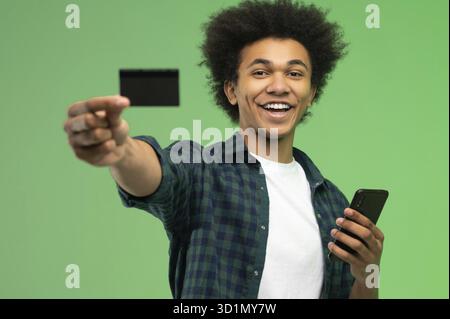 Junger afroamerikanischer Kerl mit Smartphone und Kreditkarte in den Händen Stockfoto
