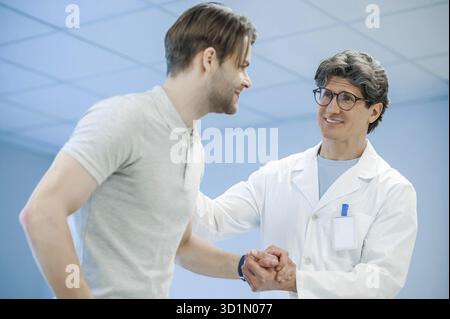 Unterstützung. Männlicher Arzt, der seine Patienten Hand hält und ihn unterstützt Stockfoto