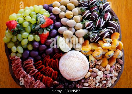 Lebendiges Bild einer Auswahl an Platten mit Aufschnitt, Süßigkeiten, Nüssen, Käse, herzhaften Snacks, und frisches Obst, perfekt für kulinarische und kommerzielle Imageverbote Stockfoto