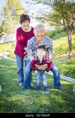 Chinesische Großeltern haben Spaß mit ihrem Mixed Race Enkel draußen Stockfoto