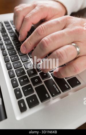 Männliche Hände, die auf einem Laptop schreiben Stockfoto
