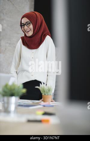Schöne arabische Frau tragen Hijab kommunizieren mit ihren Kollegen im modernen Büro. Obwohl das Glas in modernen Büro zu schießen Stockfoto