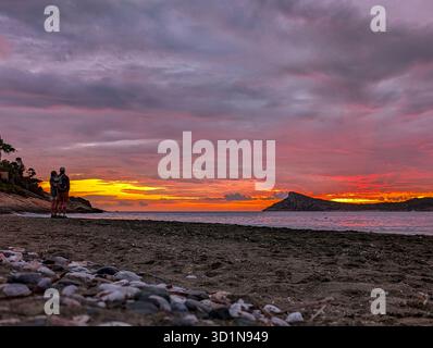 Nahaufnahme von Pebbles on the Beach. Sanfte Meereswellen und Ein wunderschöner Sonnenuntergang mit Einem violett-orangefarbenen Himmel auf der Insel Kalymnos (Griechenland) mit einer Offshore Stockfoto