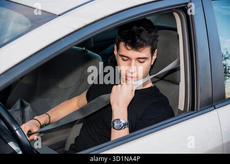 Junger Mann im Auto, der Sicherheitsgurt für die Sicherheit anlegt Stockfoto