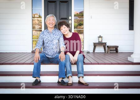 Hochrangiges chinesisches Paar, das auf den vorderen Stufen ihres Hauses sitzt Stockfoto