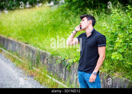 Junger Mann am Straßenrand, der anruft und auf ein Taxi wartet Stockfoto