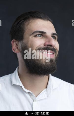 Porträt eines jungen bärtigen Mannes gegen schwarze Tafel Stockfoto