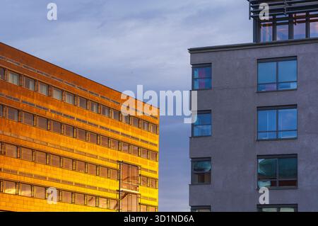 Goldenes Sonnenlicht beleuchtet die Glas- und Betonflächen von Bürogebäuden in Göteborg, Schweden, und schafft eine warme Atmosphäre bei Sonnenaufgang. Die Himmelsrichtung Stockfoto