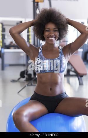 Lächelnde afroamerikanische Frau mit einer krauses Afro Frisur macht Pilates in der Turnhalle Stockfoto