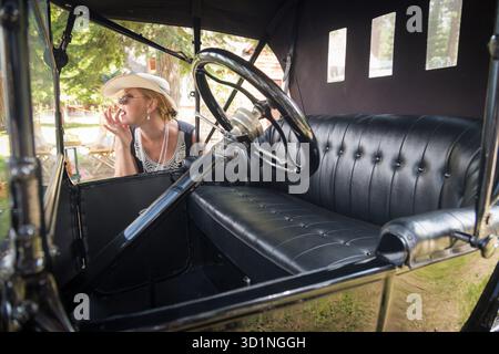 Frau im Zwanziger-Outfit in der Nähe von Antique Automobile Stockfoto