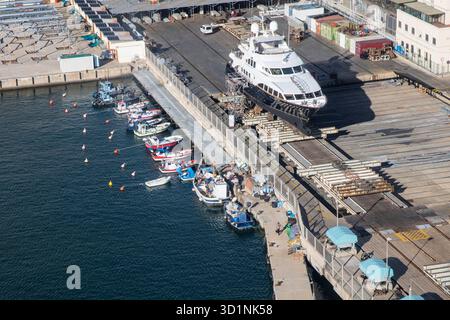 Aus der Vogelperspektive einer großen Yacht, die zum Service in einem pulsierenden City Dockyard gebracht wird. Barcelona Spanien 15.03.2024 Stockfoto