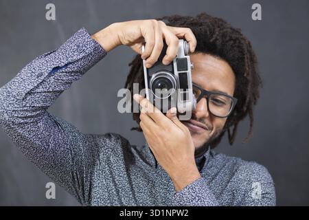 Porträt eines lächelnden Afro amerikanischen Mannes machen Foto auf Retro-Kamera an Tafel Stockfoto