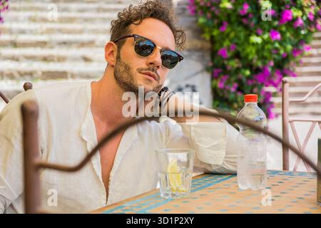 Schöner mann Trinkwasser am Tisch im Freien Stockfoto