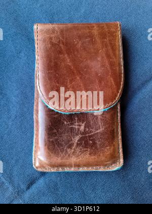 Braune handgefertigte Ledertasche für ein Smartphone auf blauem Hintergrund Stockfoto