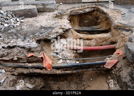 Tiefer Graben enthüllt unterirdische Versorgungsleitungen in der Stadt. Stockfoto