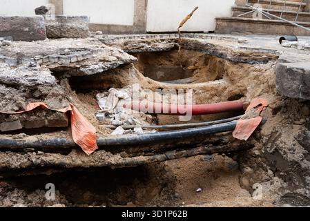 Tiefer Graben enthüllt unterirdische Versorgungsleitungen in der Stadt. Stockfoto