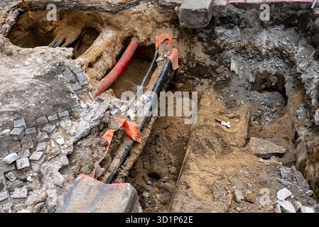 Tiefer Graben enthüllt unterirdische Versorgungsleitungen in der Stadt. Stockfoto