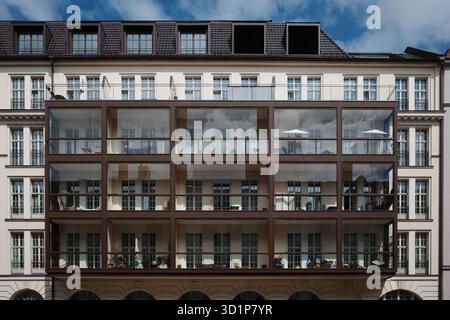 Symmetrische Fassade eines klassischen europäischen Apartmentgebäudes mit moderner, mehrstöckiger Glassonne. Stockfoto