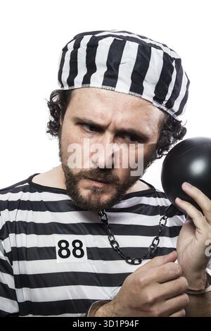 Spaß, ein kaukasischer Mann Gefangene Verbrecher mit Kette Kugel und Handschellen im Studio isoliert auf weißem Hintergrund Stockfoto