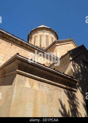 Flacher Blick auf eine orthodoxe Steinmauer und Kuppel mit starkem Sonnenlicht und Schatten in Tiflis, Georgien. Stockfoto