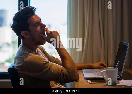 Junger Mann mit Hausaufgaben am Computer-Schreibtisch Stockfoto