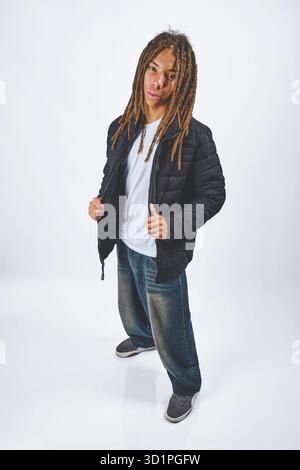 Junger Mann mit Dreadlocks in einer Pufferjacke und Baggy Jeans Stockfoto