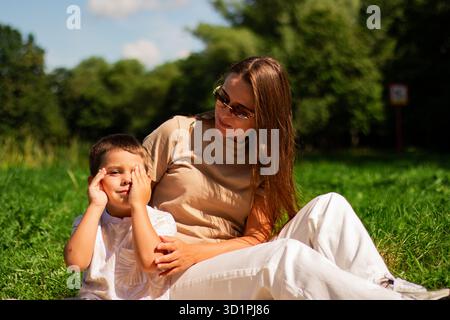 Mutter mit Kind, die Spaß im öffentlichen grünen Park hat. Glückliche Mutter lacht zusammen mit dem Sohn. Hochwertige Freizeit im Freien. Stockfoto