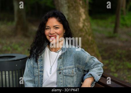 Frau genießt friedliche Momente im öffentlichen Park. Nachdenkliche Frau. Ehrlicher Moment. Gefühle der Ruhe Achtsamkeit und Verbindung mit der Natur. Stockfoto