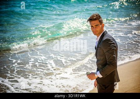Schöner Mann im klassischen Anzug auf Strand Stockfoto