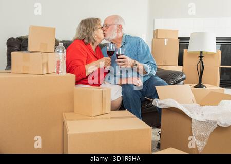 Seniorenpaar Für Erwachsene, Das Weingläser Serviert, Umgeben Von Umzugskartons Stockfoto