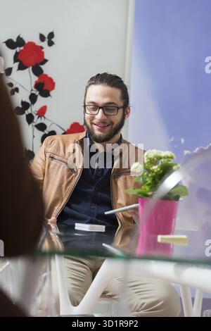 Glücklicher junger arabischer Geschäftsmann mit Bart, der in einem modernen Startup-Büro arbeitet Stockfoto