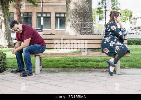 Unglückliches Mixed Race-Paar, das sich auf der Park Bench gegenübersteht Stockfoto