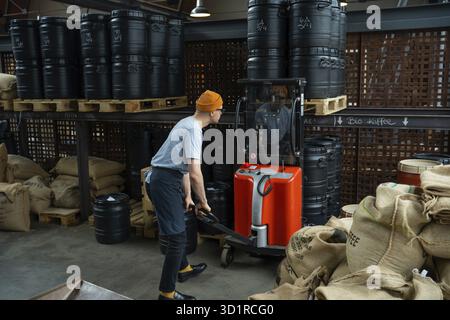 Hipster-Mann in Hut und Schürze, der Fabrikarbeiter, der Kaffeebohnen für die Kaffeezubereitung vorbereitet Stockfoto