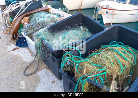 Fischernetze in Black Boxes am Hafen mit Booten im Hintergrund. Stockfoto
