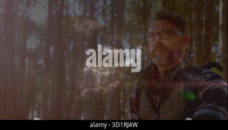 Männlicher Wanderer trägt Brille, Weste, atmet Dampf im Sonnenuntergang Wald, trägt Rucksack, Kopierraum Stockfoto