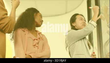 Zusammenarbeit mit Kollegen aus Glasplatten, die Diagramme mit Markern im Konferenzraum oder im Kopierraum zeichnen Stockfoto