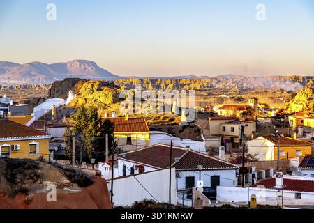 Guadix, Granada - Spanien - 24.01.2024: Ein Panoramablick auf Guadix in Andalusien, Spanien, zeigt weiß getünchte Höhlenhäuser und Schornsteine vor einem Dramati Stockfoto