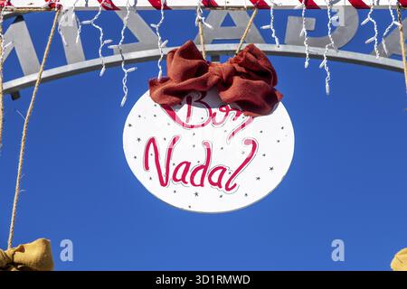 Denia, Alicante - Spanien - 22.12.2023: Hellblauer Himmel mit „Bon Nadal“-Weihnachtsschild und roter Schleife Stockfoto