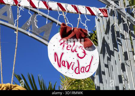Denia, Alicante - Spanien - 22.12.2023: Hellblauer Himmel mit „Feliz Navidad“ Weihnachtsschild in spanischer Sprache und rotem Band Stockfoto